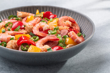 Jambalaya rice with chicken, shrimp, sausage and vegetables in plate on gray concrete table