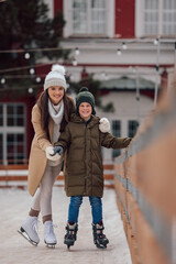 Portrait of smiling mother and son, enjoying on the ice, skating.