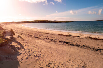 Dog's bay beach at sunset. Sun flare. County Galway, Ireland, Connemara. Popular tourist place known for sand and stunning view and clean blue ocean water. Irish nature scene.
