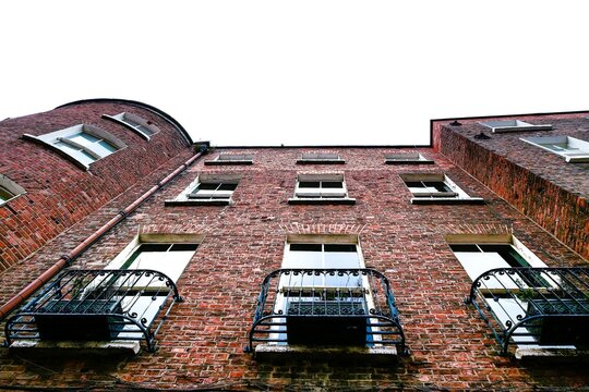 Facace of an old red brick building. Look up view. Retro style architecture. Old town or urban area.
