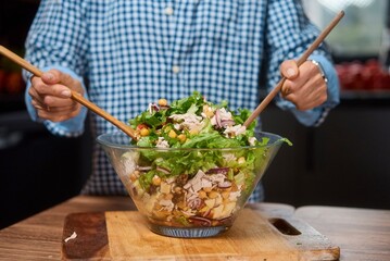 Young woman is preparing vegetable salad in the kitchen. Healthy Food. Vegan Salad. Diet. Dieting Concept. Healthy Lifestyle. Cooking At Home. Prepare Food. Clothe up.