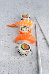 A set of sushi nigiri and rolls with salmon and chopsticks on a stone background. Japanese dish with fresh fish
