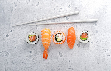 A variety of sushi nigiri and maki with salmon and chopsticks on a stone background. Asian cuisine...