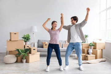 Happy european millennial man and lady dancing in living room interior with cardboard boxes