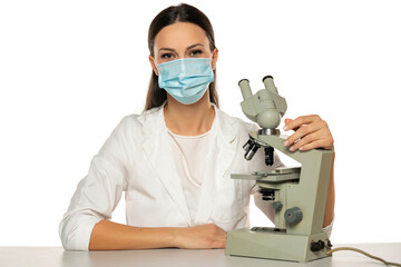 Fototapeta na wymiar Portrait of female scientist with microscope and face mask