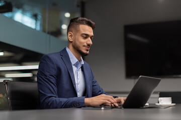 Side view of middle eastern businessman typing on notebook