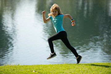 Fototapeta na wymiar Kids running or jogging near lake on grass in park. Boys runner jogging in outdoor park. Running is a sport that strengthens the body. Morning jogging.