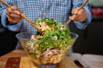 Young woman is preparing vegetable salad in the kitchen. Healthy Food. Vegan Salad. Diet. Dieting Concept. Healthy Lifestyle. Cooking At Home. Prepare Food. Clothe up.