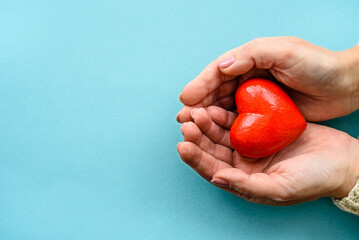 A red heart in his hands on a blue background.