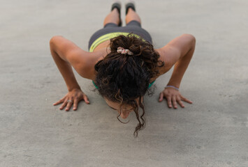 shot of slim lady dressing sport clothes doing push ups in a exterior place