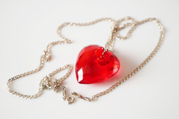 red pendant as heart with silver chain on white background, valentine's dating