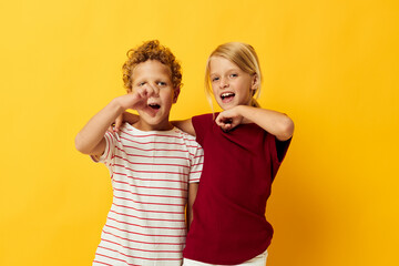 Cute stylish kids standing side by side posing childhood emotions yellow background