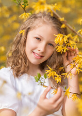 Portrait of a girl with yellow forsythia flowers. Spring Garden