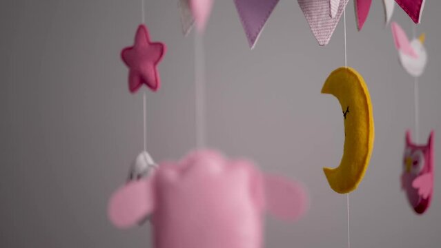 baby mobile with blue hand-stitched animal and bird toys with yellow moon on white wall background. spinning on the baby's crib in the room