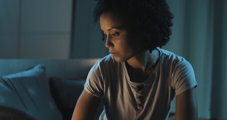 Sad woman sitting on bed at night