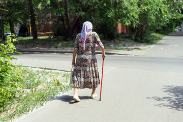 An elderly woman with a cane walks around the city.