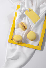 French macaroon cookie in yellow frame on white textile