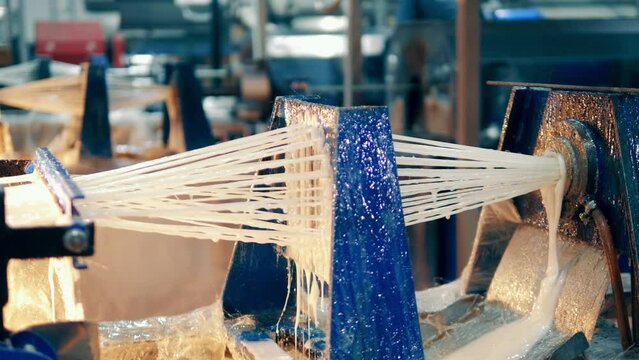 Strings of fiberglass in mastic are going through a factory machine