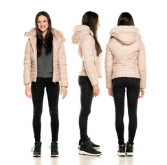 Front, side and rear view of a young woman in winter jacket, and black jeans posing on a white