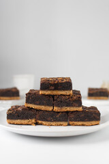 Fudgy brownies stacked on a white plate, fudgy caramel brownies with a cookie crust, stack of brookies, thick brownie bars