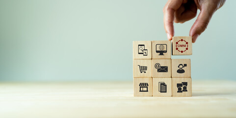 Omnichannel marketing concept. Digital online marketing commerce sale. For customer engagement by integrated online and offline channels. Hand holds wooden cube with omni text standing with omni icon