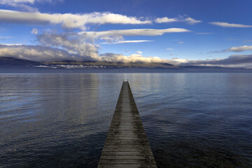 Ponton sur le lac de Neuchâtel au centre avec le jura en arrière plan.