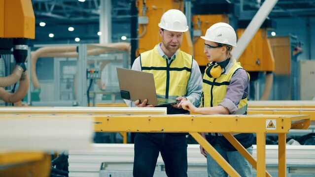 Factory workers are discussing a fiberglass frame
