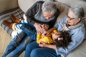 Portrait of happy grandparents with child playing together at home