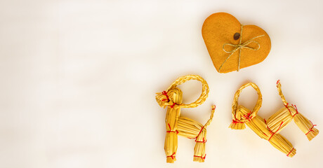 Christmas scandinavian straw goats with cookies on light background with copyspace