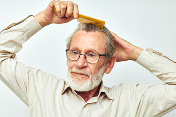 Elderly man combing hair in studio