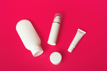 Closeup of white tubes for various cosmetics on a pink background. With copy space.
