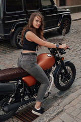 Fototapeta na wymiar Pretty woman motorcyclist riding motorbike on alley in town