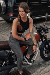 Tattooed beauty sitting on retro styled bike on alley