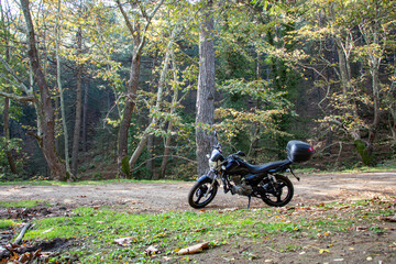 Motorcycle alone on the road. Touring in the forest. Motorcycle on the forest road.  Motorcycle in nature parking on a path.