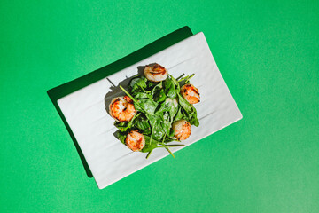 Fototapeta na wymiar Salad with shrimps and arugula on white dish on colored background