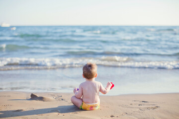 Baby boy sitting on beach sea