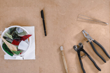Top view photo of pliers, scissors and cutter for mosaic making on wooden table