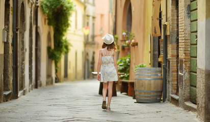 Young girl exploring medieval streets of picturesque resort town Bolsena, situated on the shores of Italy's largest lake, Lago Bolsena, Italy.