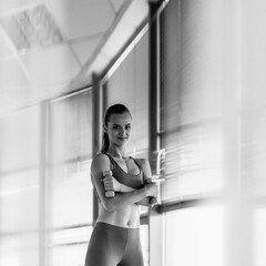 Portrait of active woman in sportswear lifting dumbbells to be fit, monochrome image aspect ratio...