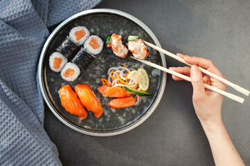 Traditional japanese nigiri sushi with salmon placed between chopsticks