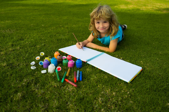 Kids painting with paints color and brush in park outdoor. Happy child playing outside. Drawing summer theme. Imagination kids concept.