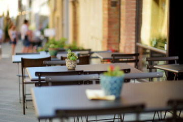 Empty restaurant table in medieval street of Montalcino town, located on top of a hill top and surrounded by vineyards, known worldwide for the production of wine. Tuscany, Italy.