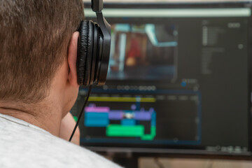 Freelancer with headphones edits videos using postproduction software while working at home for a...