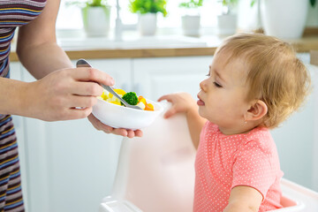 The baby eats vegetables on a chair. Selective focus.