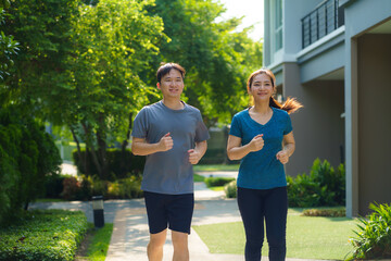 Asian couple are jogging in the neighborhood for daily health and well being, both physical and...