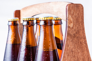 Close-up of wet six bottles necks of beer in a wooden case on a white background. Alcoholic drinks...