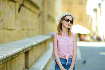 Young girl exploring in Pienza, a village located in the beautiful Tuscany valley, known as the 'ideal city of the Renaissance' and a 'capital' of pecorino cheese.