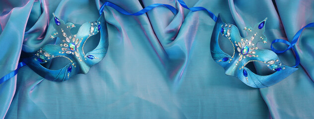 Photo of elegant and delicate Venetian mask over blue silk background