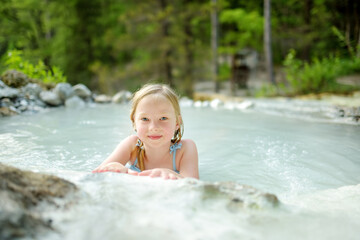 Young girl bathing in Bagni San Filippo, small hot spring containing calcium carbonate deposits, forming white concretions and waterfalls. Geothermal pools and hot springs in Tuscany, Italy.