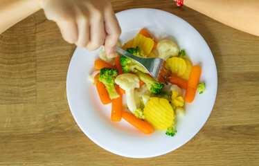 The child eats vegetables on a chair. Selective focus.